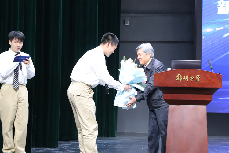 1744677761473436.jpg 图片4志愿者为王树国校长献花.JPG